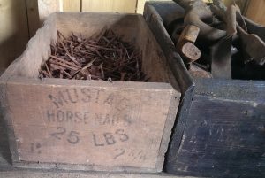 A box of horse shoes nails sits on the side in the Smiddy