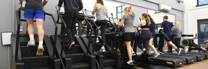 People exercising on treadmills and stair machines in a gym